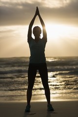 Wall Mural - Sporty brunette stretching on the beach