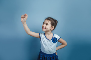 European-looking girl of five years draws in air on a gray backg