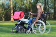 © RioPatuca Images - Mutter im Rollstuhl schiebt Kinderwagen im Park