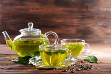 Wall Mural - Cups of green tea on table on wooden background
