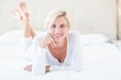 © WavebreakmediaMicro - Smiling blonde woman lying on the bed