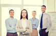 © Syda Productions - smiling businesswoman in office with team on back