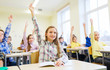 © Syda Productions - group of school kids raising hands in classroom