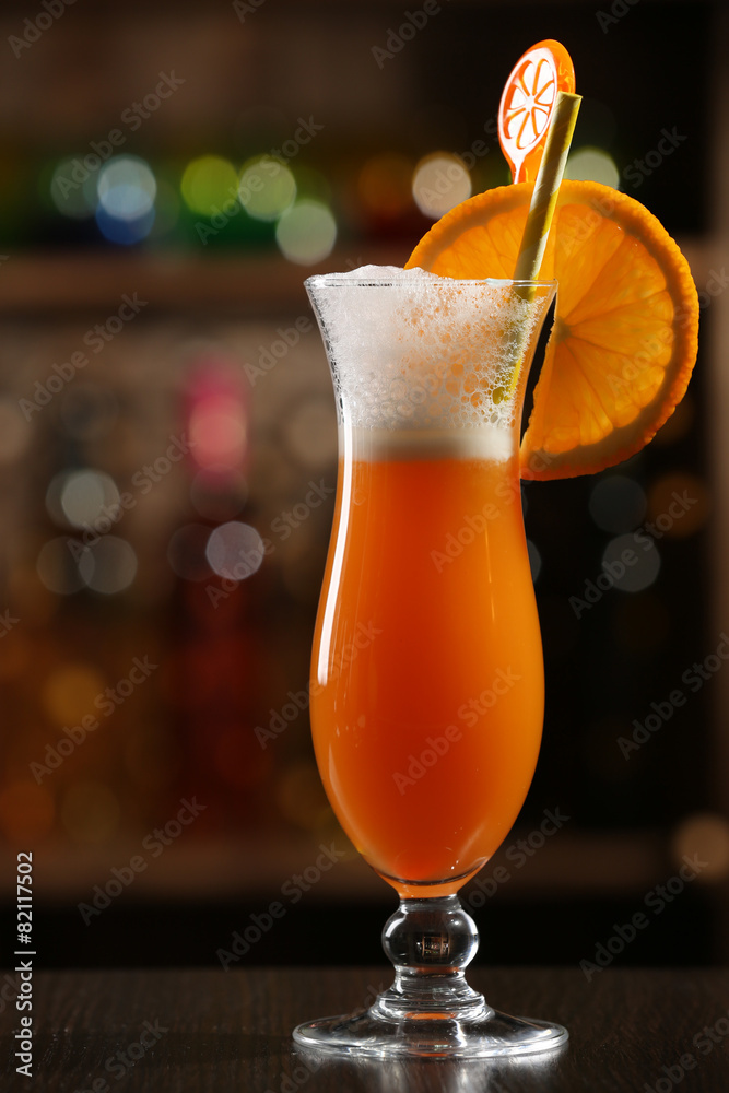 Glass of fruit cocktail in bar on bright blurred background