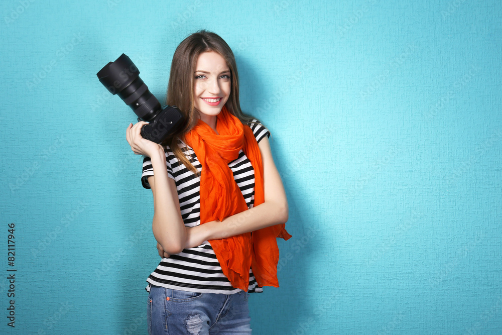 Young female photographer taking photos on blue background
