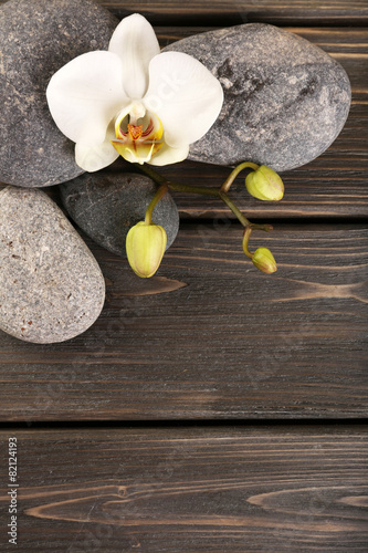 Fototapeta na wymiar Spa stones and orchid flower on wooden background