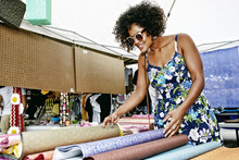 Mixed Race Woman Examining Fabrics At Flea Market