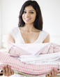 © JGI/Blend Images - Mixed Race woman holding folded laundry