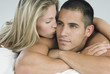 © Gabriela Medina/Blend Images - Hispanic woman kissing boyfriend in bed