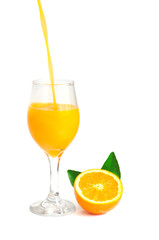 orange juice pouring into glass with orange slice and leaf, isol