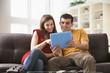 © Mike Kemp/Blend Images - Couple using digital tablet on sofa