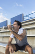 © Marc Romanelli/Blend Images - Hispanic athlete resting on bleachers