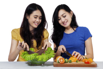 Cheerful girls cooking vegetables salad