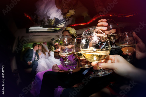 Photographie Happy groom and the bride in the car together with friends