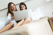 © NDABCREATIVITY - Two beautiful women using a notebook while in bed