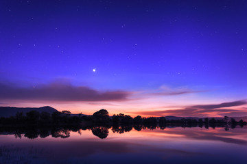 Beautiful night sky with stars, clouds and reflections in the wa