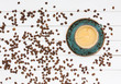 Cup of coffee and coffee beans on white wooden table. Top view