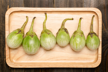 Raw aubergines are arrangement on wooden plate