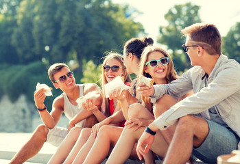 Wall Mural - group of smiling friends sitting on city square