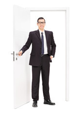 Poster - Young businessman posing in front of a door