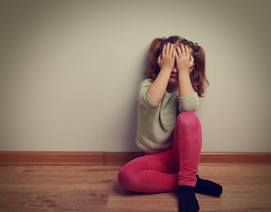 Wall Mural - Frightened crying kid girl sitting on the floor with closed face