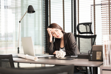 tired and sleepy young business woman at the desk with a laptop