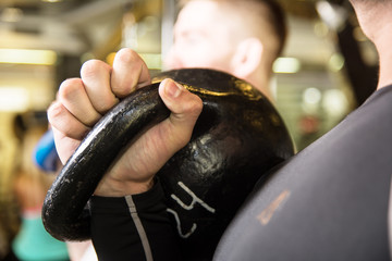 Closeup swing kettlebell training two young men in the gym