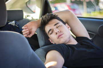 Young man sleeping inside his car, exhausted