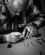 Senior watchmaker repairing an old pocket watch. Black and white.