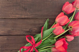 Fototapeta  - Bouquet of red tulips on wooden background with space for text