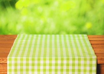 Poster - Abstract. Empty wooden table with tablecloth over bokeh