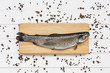 Trout fish on cutting wooden board with peppercorns