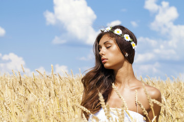 Wall Mural - Young woman in a wheat golden field