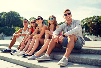 Wall Mural - group of smiling friends sitting on city street