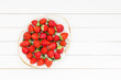 Fresh strawberries in plate on white wooden table. Top view