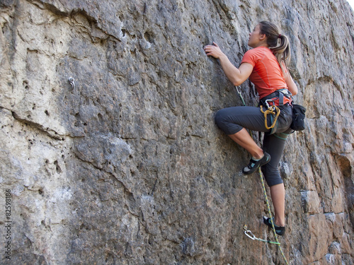 Fotografie, Obraz Young woman with rope climbs on the rock.
