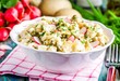 potato salad with fresh radishes and dill in a white bowl
