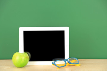 Canvas Print - Tablet on table, on green blackboard background