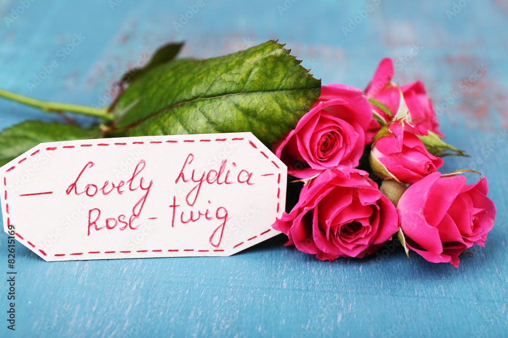 Beautiful rosy twig with tag on wooden background