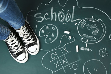 Wall Mural - Female feet on blackboard background with inscriptions and sketches