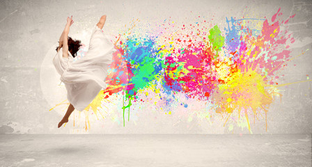 Happy teenager jumping with colorful ink splatter on urban backg