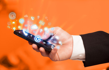 Business man holding smart phone with media icons