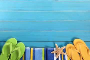 Summer beach background border with sunbathing towel and accessories in a line row on old blue wood decking deck photo