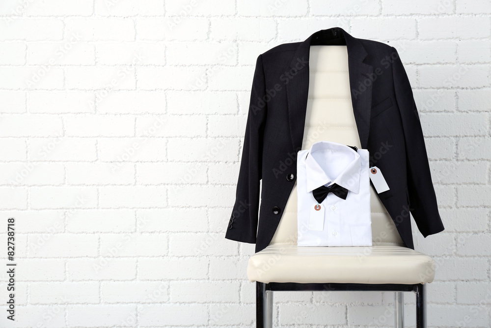 School clothes for boy on chair, on white wall background