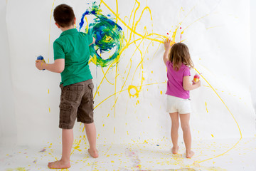 Two young children freehand painting on a wall