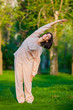 © satyrenko - Practicing yoga in the morning, with trees  background
