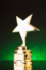 Wall Mural - gold star trophy against green illumination background