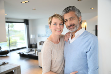 Wall Mural - Smiling middle-aged couple standing in brand new home