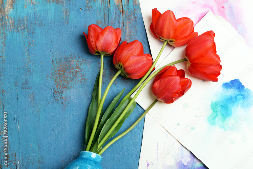 Red tulips in vase on wooden background top view