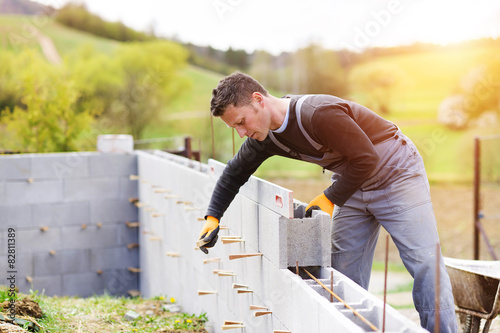 Fotografía Bricklayer putting down another row of bricks in site